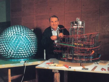 Franz Mack between two models of the early Eurosat, with the exterior on the left and the interior on the right.