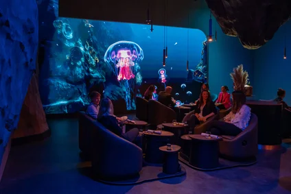 Guests in the Ocean room at Eatrenalin in Floating Chairs in front of the large LED screen.