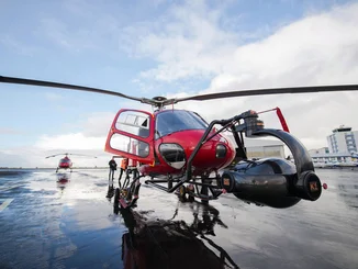 Roter Hubschrauber mit großer Kamera filmt Szenen für das Flying Theater.
