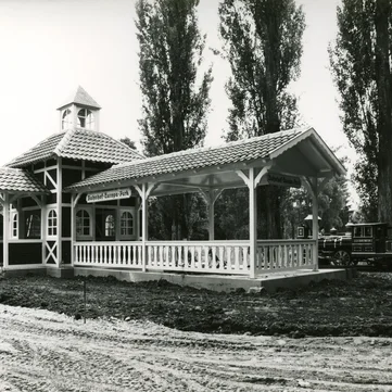 Black-and-white photograph of the Panorama Train Station building with a train pulling in and construction work taking place around it.
