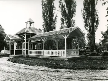 Black-and-white photograph of the Panorama Train Station building with a train pulling in and construction work taking place around it.