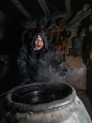 Darsteller in der Scare Attraction Tarot House Kapuzen-Darsteller vor Fass in der Scare Attraction Tarot House.