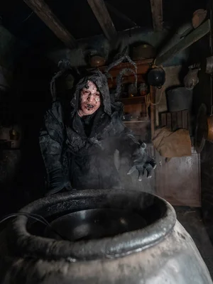 Darsteller in der Scare Attraction Tarot House Kapuzen-Darsteller vor Fass in der Scare Attraction Tarot House.