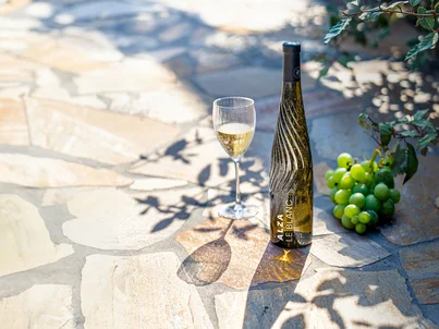 Das originelle Flaschendesign von ALZA Le Vin Eine Flasche ALZA Le Vin und ein Weinglas daneben. Das originelle Flaschendesign glitzert im Sonnenlicht.