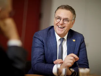 Roland Mack Roland Mack sits at a conference table and smiles.