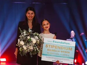 Katja Mack überreicht einem Mädchen einen Scheck für ein Stipendium durch den Förderverein Talent Foundation e.V.
