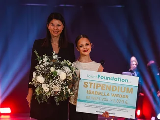 Katja Mack überreicht einem Mädchen einen Scheck für ein Stipendium durch den Förderverein Talent Foundation e.V.