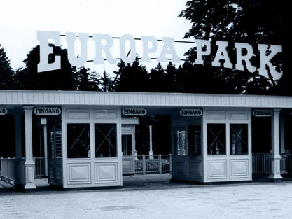 Ehemaliger Haupteingang des Europa-Park mit vier Kassenhäuschen und Schriftzug, umgeben von hohen Bäumen.