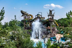 The Svalgurok slide tower at Rulantica on a sunny day, complete with waterfall, splashing water and guests.