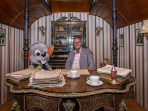 Roland Mack in a circus wagon Roland Mack sits at a desk in a historic circus wagon with a large Ed soft toy.