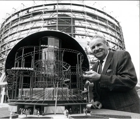 Franz Mack presents a model of Eurosat in front of the construction site. Franz Mack stands in front of the Eurosat construction site and presents a detailed model showing the inner workings of the attraction.