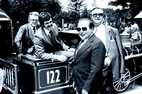 Roland Mack, rieur, est assis sur la locomotive du train panoramique, entouré de visiteurs de marque.