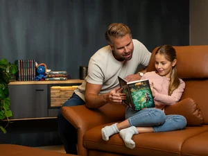 Rulantica – Die Verschwörung der Götter Ein Mann liest mit einem Kind den zweiten Band der Rulantica Saga.