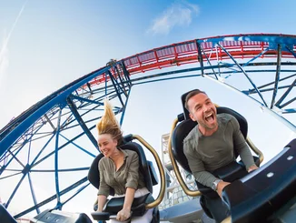 Zwei Personen genießen die Fahrt auf der Achterbahn Dynamite.