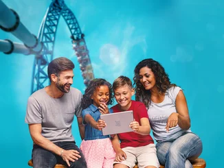 VEEJOY – The exclusive streaming platform A family is looking at content on a tablet. A rollercoaster can be seen in the background.