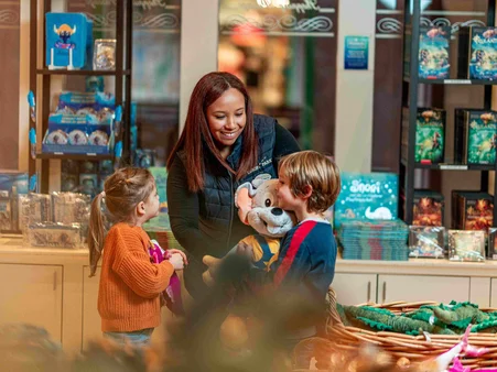 Europa-Park shopping An employee in a merchandise shop at Europa-Park presents an Ed Euromaus soft toy to two delighted children.