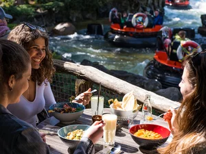 Freundesgruppe genießt das frische Essen im Restaurant SPICES im Europa-Park mit Blick auf das Fjord Rafting.