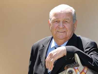 Portrait of Europa-Park founder Franz Mack leaning on a carousel horse.