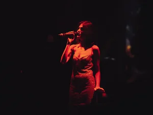 Exklusive Auftritte nur für Sie Eine Frau singt im Dunklen, sie wird nur von einer Lampe beleuchtet.