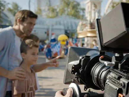 Casting-Datenbank Mann und kleiner Junge stehen vor einer professonellen Videokamera im Europa-Park und werden gefilmt.