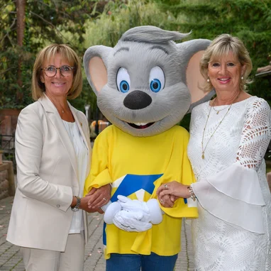 Marianne and Mauritia Mack together with Ed Euromaus in a natural setting. Marianne and Mauritia Mack with Ed Euromaus against a backdrop of trees and flowers.