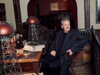 Michael Mack FOCUS STYLE Michael Mack at Nikola Tesla's desk, on which there are two Wardenclyffe Towers.