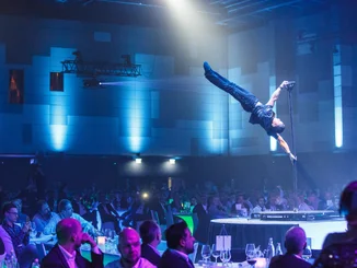 Confertainment Showprogramm Ein Mann zeigt beeindruckende Akrobatik-Figuren an einer Stange.