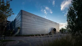 Futuristic EATRENALIN building at dusk with lettering on the building and surrounded by shrubs.